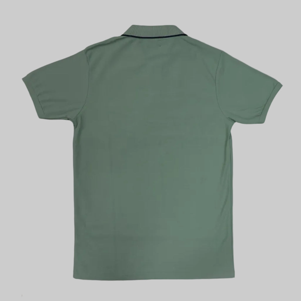 Green t-shirt on a white floor with a person's legs in the background